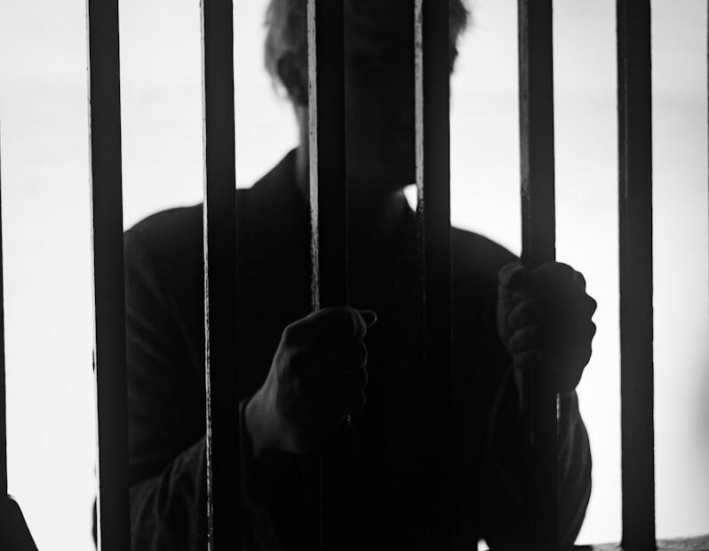 a man standing behind bars in a jail cell